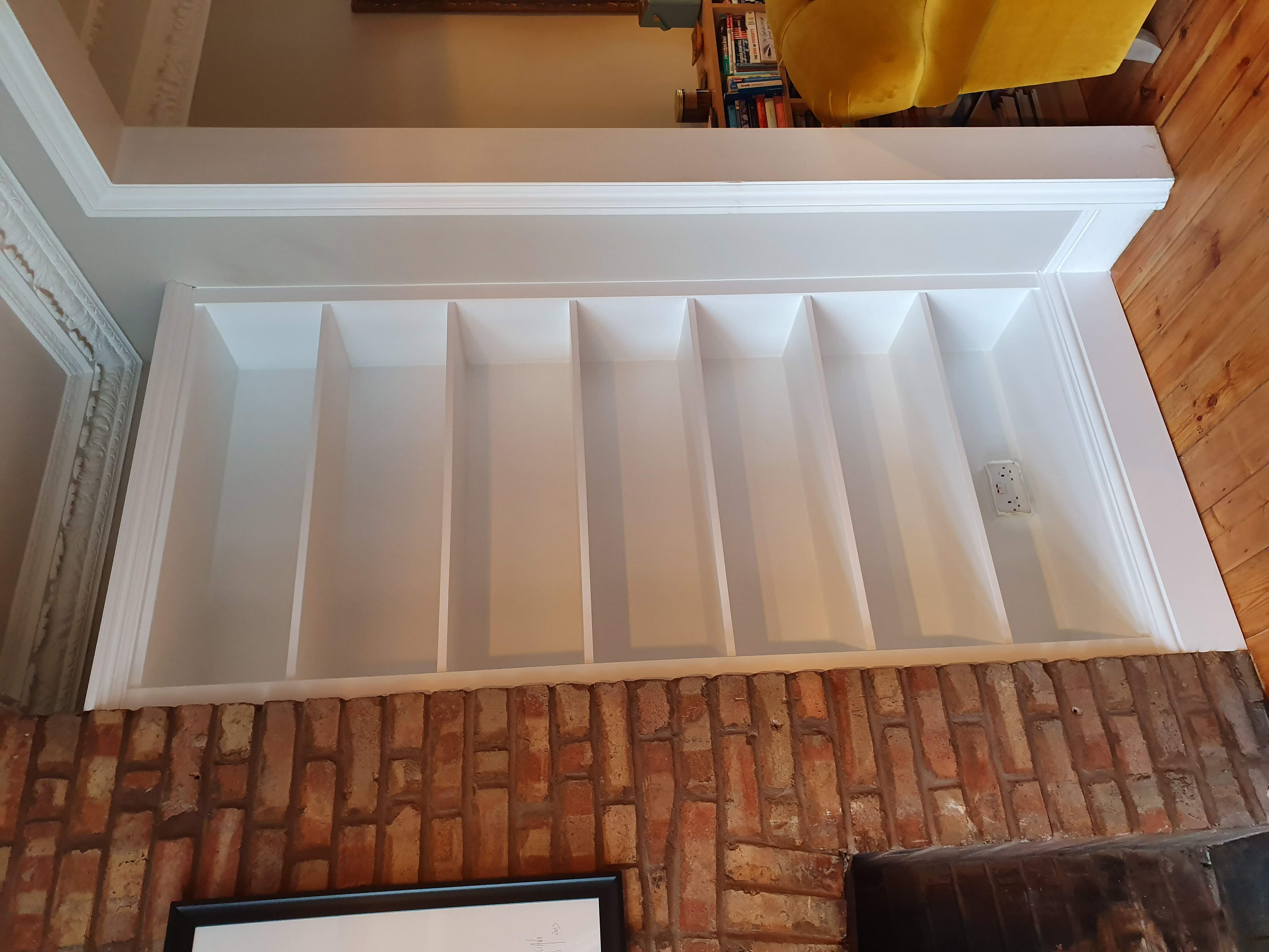 Traditional white alcove shelving unit in a living room, nestled beside a brick fireplace