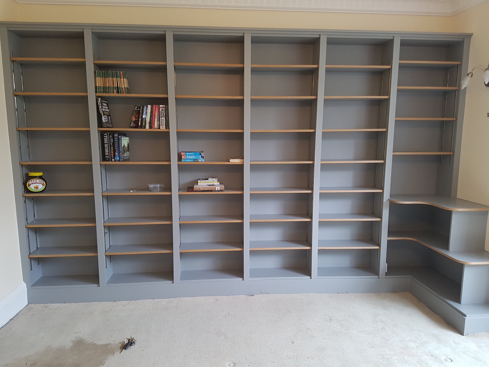 Floor-to-ceiling grey bespoke bookcases with oak shelves